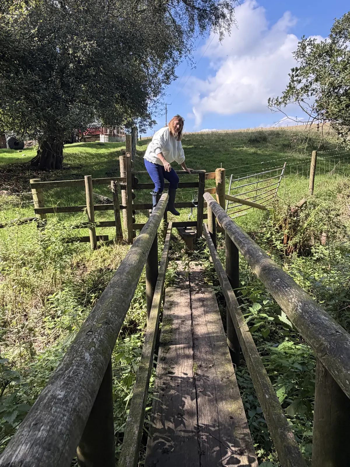 Angela crossing a narrow wooden footbridge on the walk to The Jervis Arms