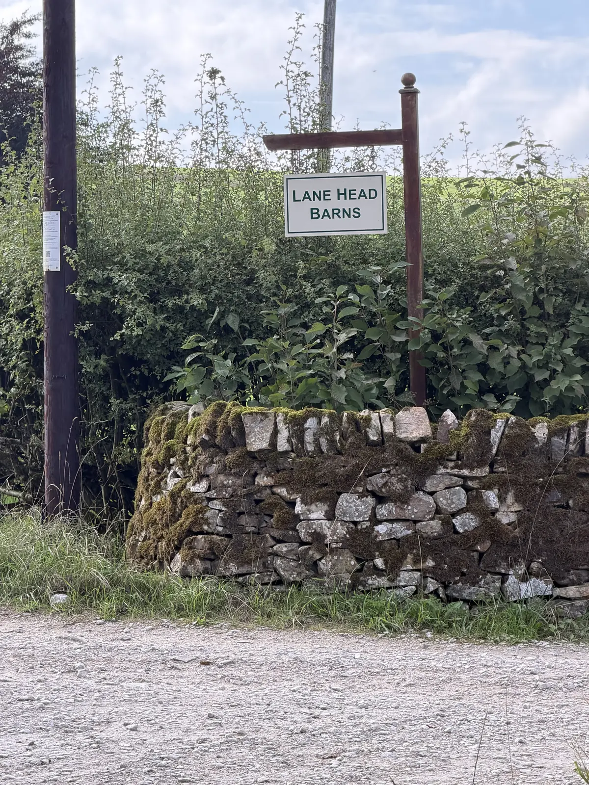 The Lane Head Barns sign beside a dry-stone wall at the end of the walk