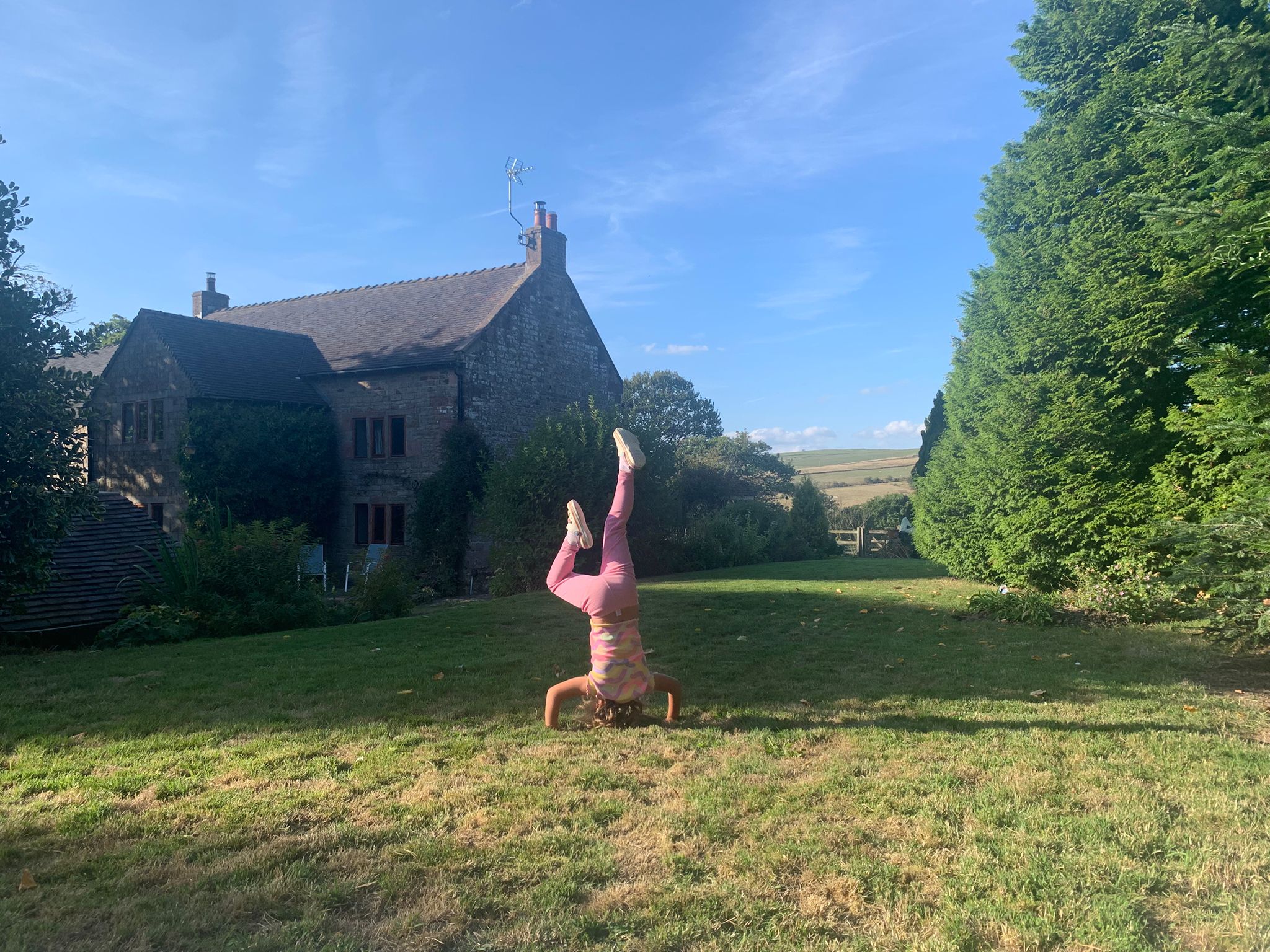 Alice doing a headstand on the lawn at Lane Head Farm, with the Staffordshire Moorlands behind
