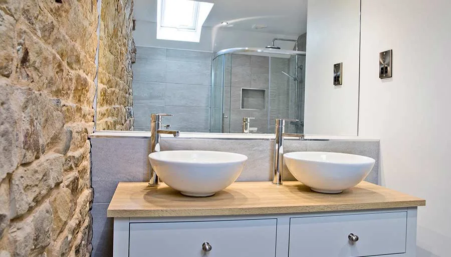 En-suite bathroom at Mixon View with exposed stone wall and twin basins